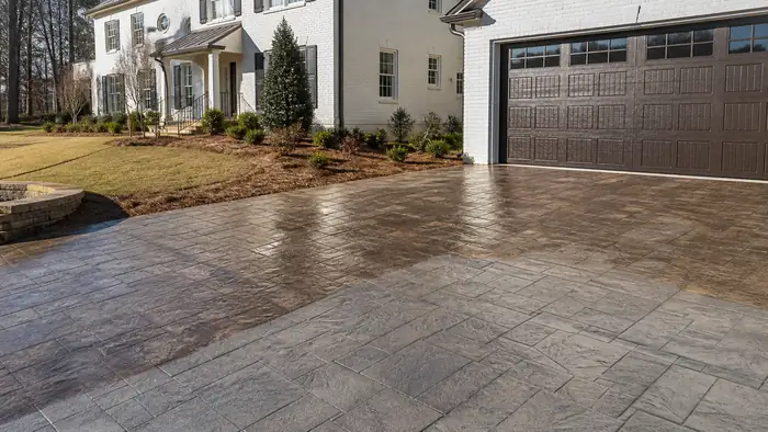 A roller applies sealer to a stamped patio surface. at a painted-white-brick two-story home in Marietta, GA, under low winter sun.