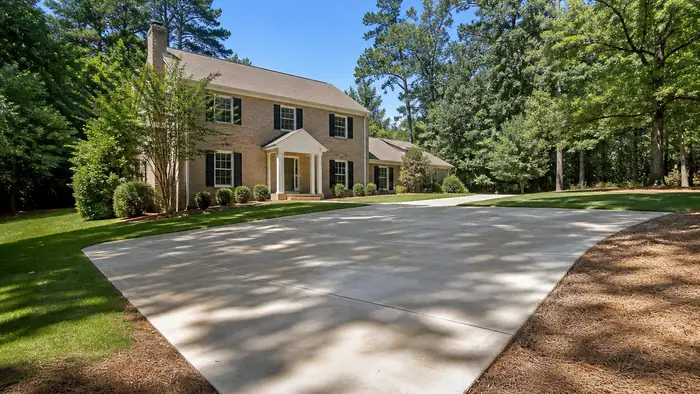 concrete construction services completed by a local contractor at a tan-brick colonial in Marietta, GA, in clear late-morning sun.