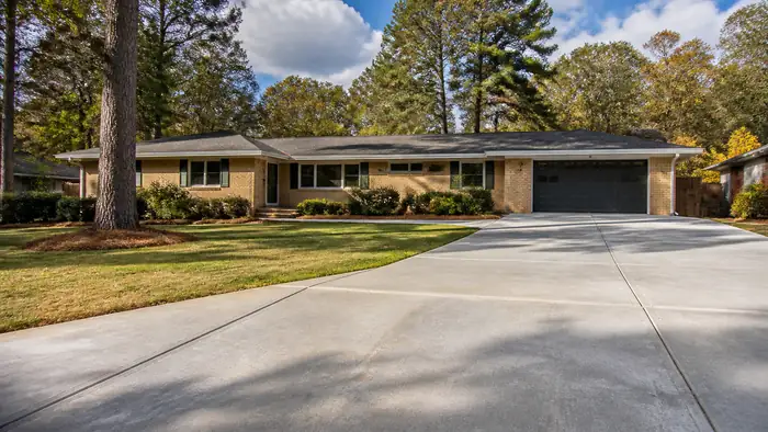 concrete driveway crack repair completed by a local contractor at a buff-brick ranch home in Marietta, GA, under broken cloud.