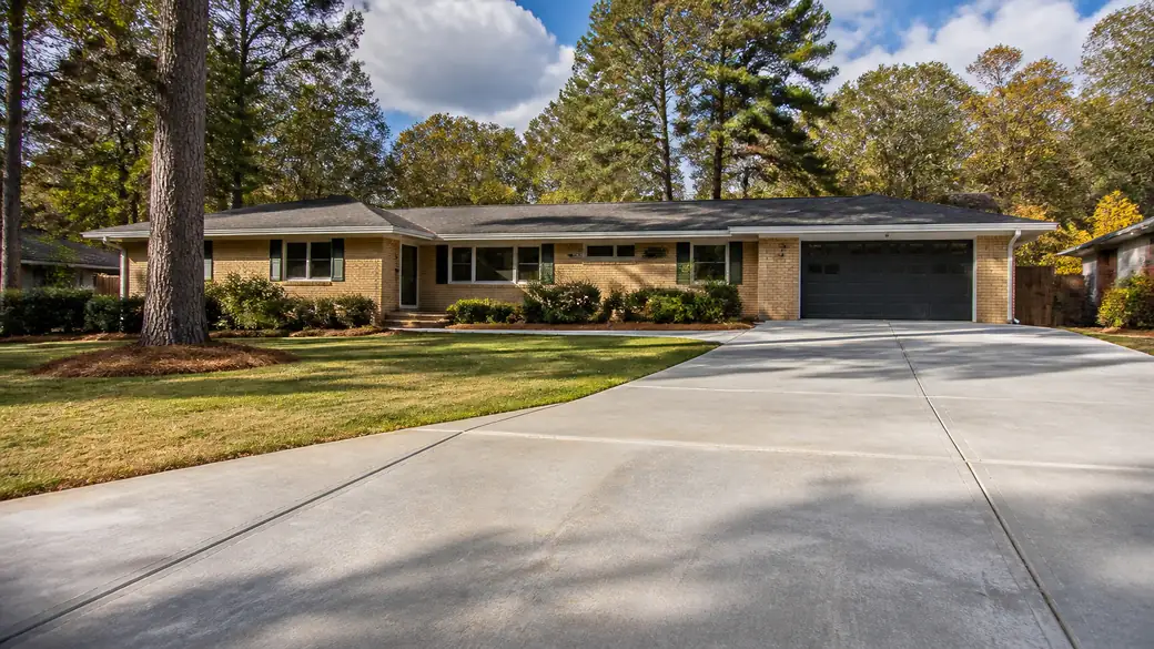 concrete driveway crack repair completed by a local contractor at a buff-brick ranch home in Marietta, GA, under broken cloud.