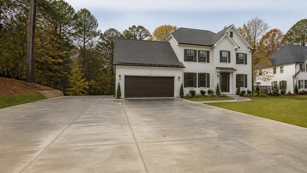 concrete flooring installation completed by a local contractor at a painted-white-brick two-story home in Marietta, GA, under bright midday cloud.